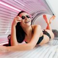 girl lies in a horizontal tanning bed in protective glasses