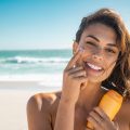 Smiling woman applying sunscreen